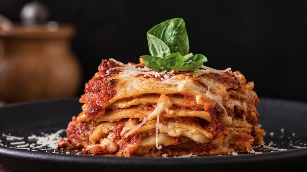 Illustrative image of a layered lasagna with basil and grated Parmigiano.